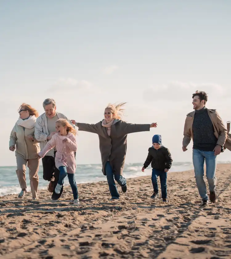 Suplementy diety Iskial na bazie oleju z wątroby rekina na wsparcie odporności. Wielopokoleniowa rodzina na plaży w wietrzny jesienny lub wiosenny dzień.
